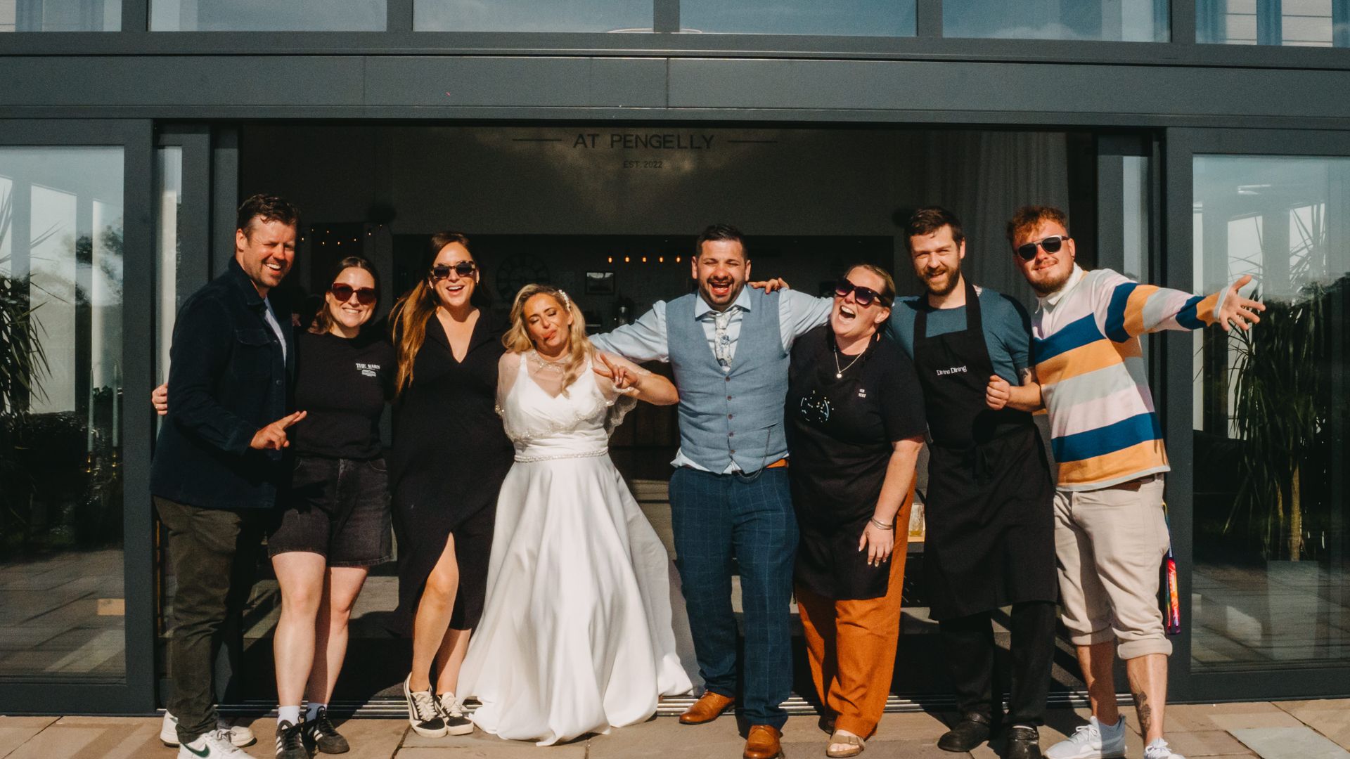 The wedding couple, friends and Pengelly colleagues standing the the doorway of the