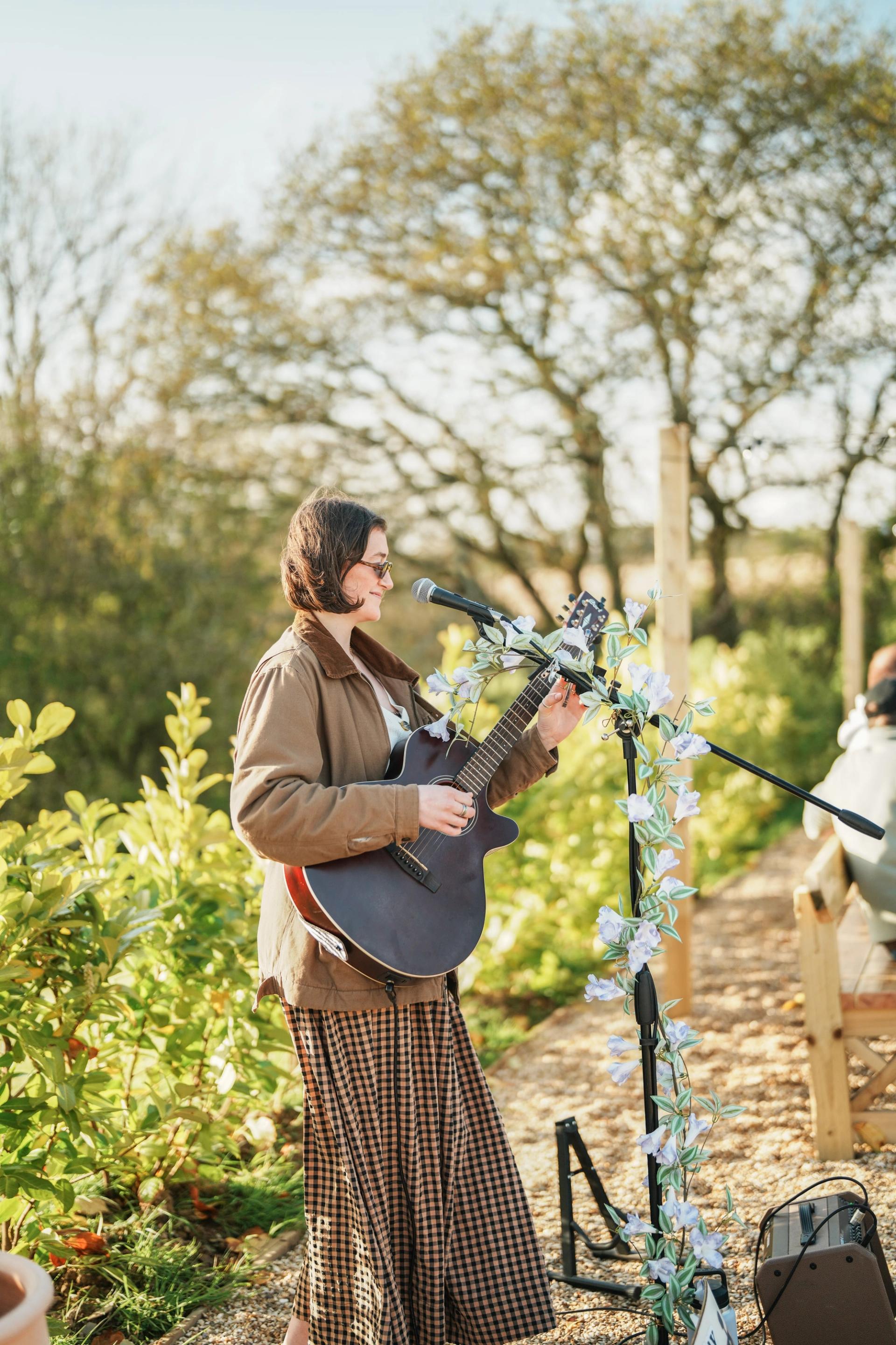 Musician with a guitar and microphone standing in the kitchen garden