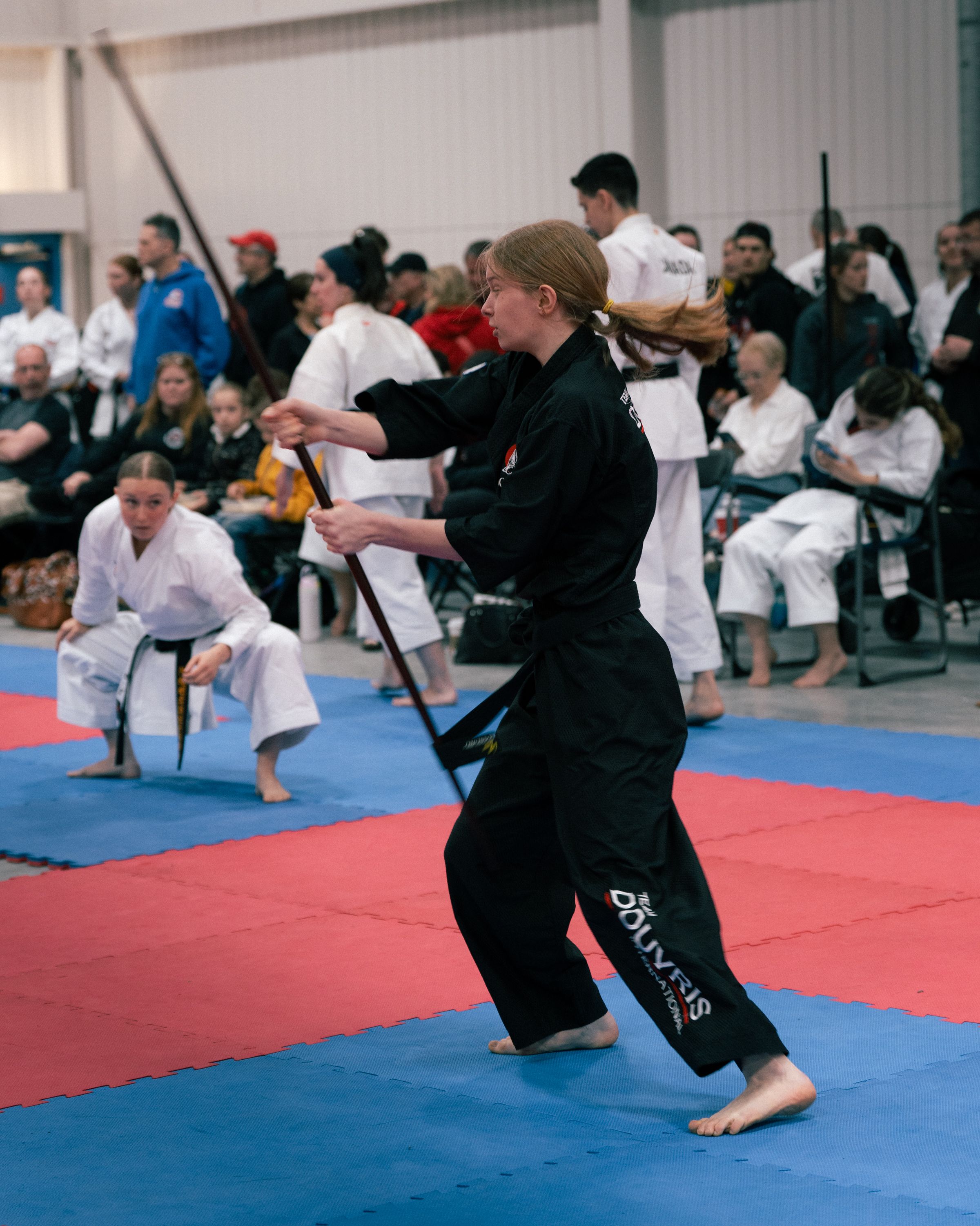 Young martial arts students at Douvris bowing respectfully at the edge of the dojo mat, demonstrating responsibility and focus.