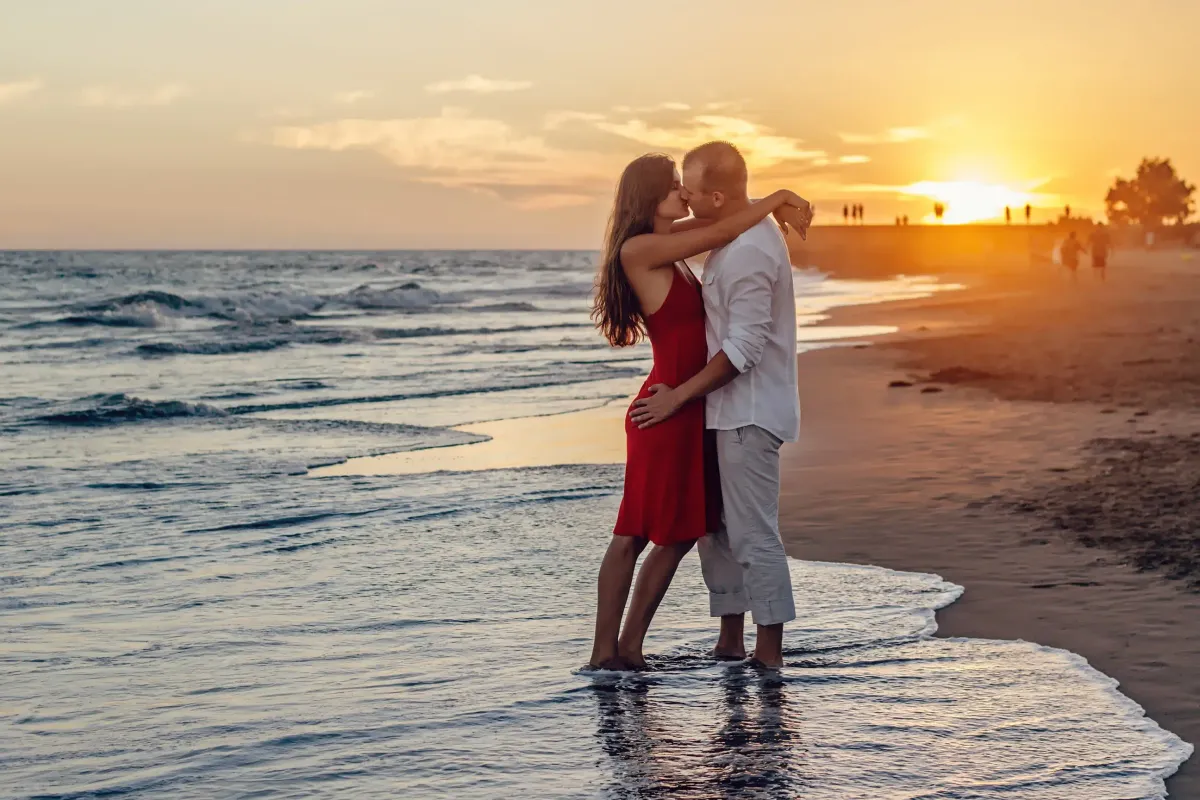 A couple hugging each other at the beach during sunset