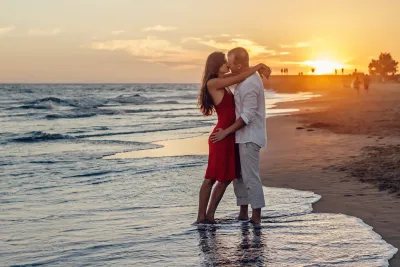 A couple hugging each other at the beach during sunset