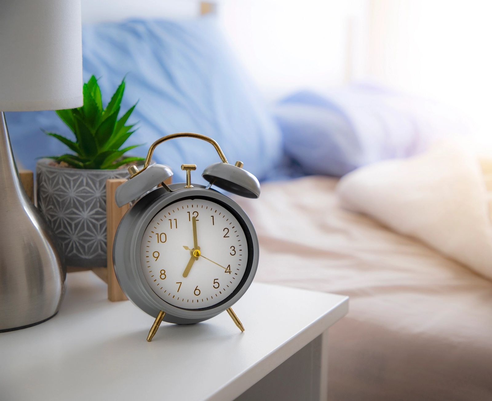 Floor model nightstand with bedside clock and softly styled bedroom background