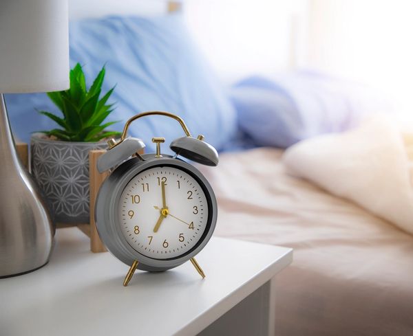 Floor model nightstand with bedside clock and softly styled bedroom background
