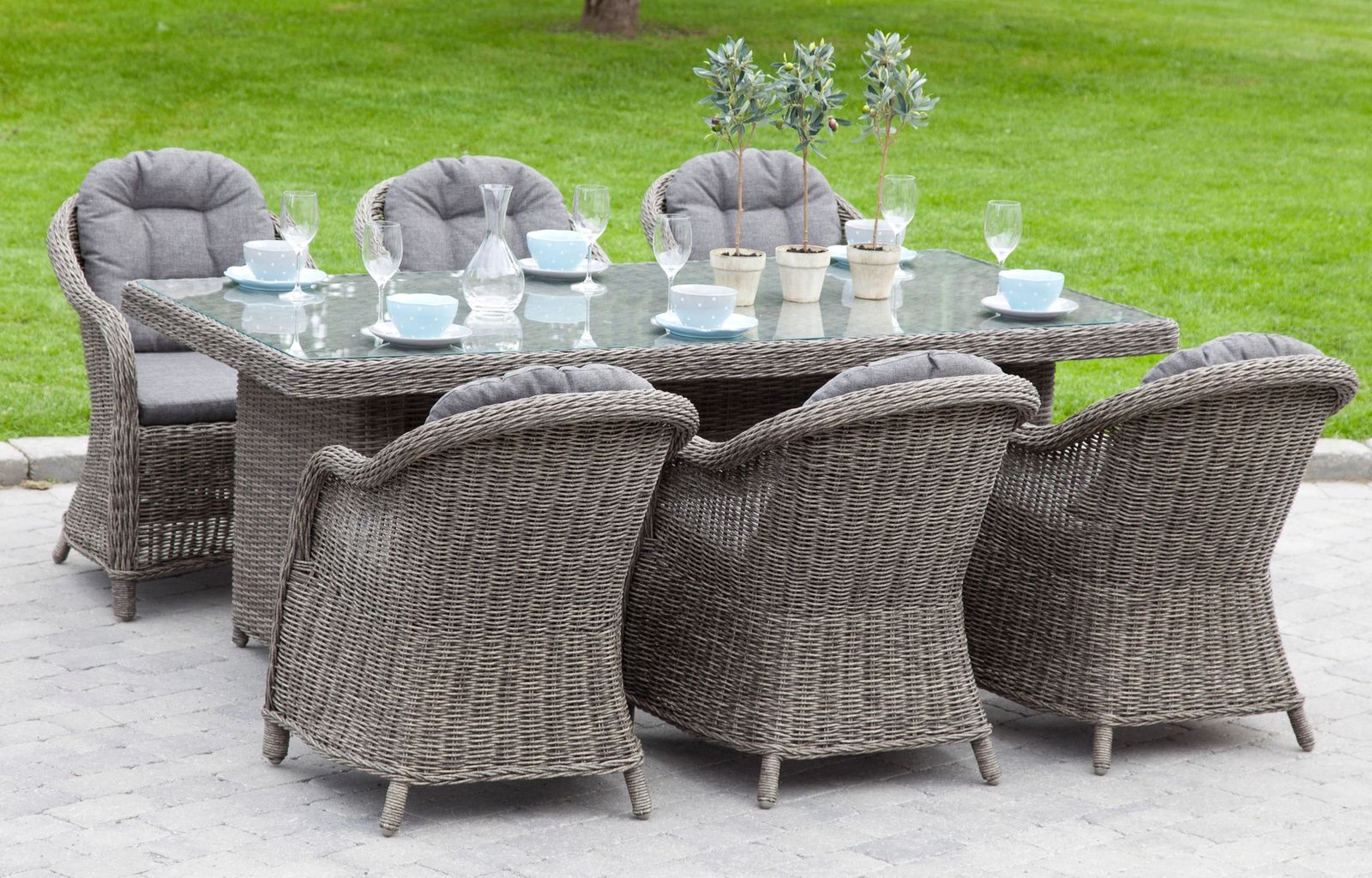 Wicker patio dining set with table and chairs on outdoor stone patio