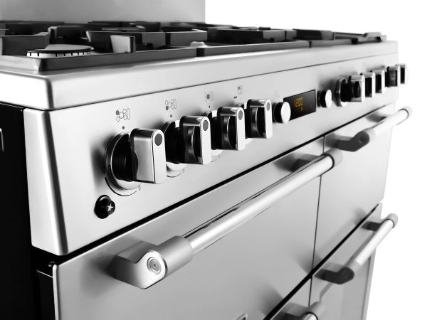 Stainless steel gas range and oven with control knobs displayed in an appliance showroom