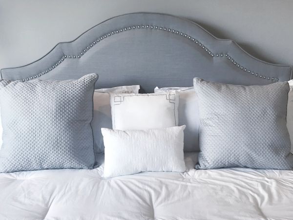Upholstered floor model bed with decorative headboard and layered pillows