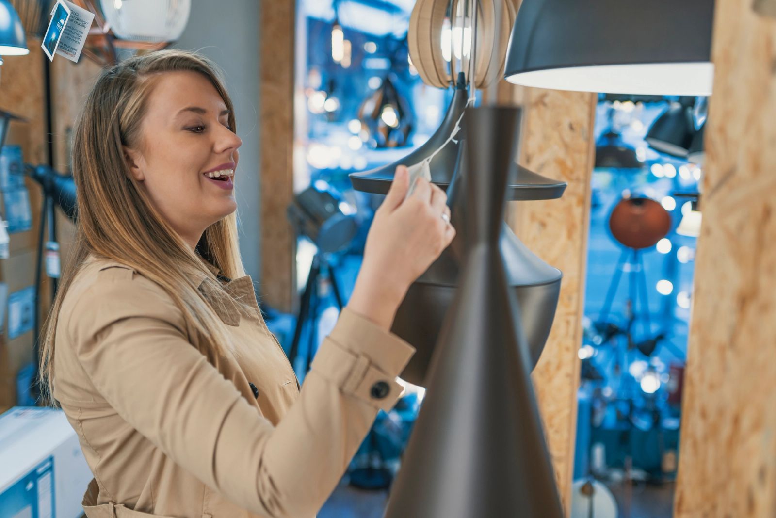 Woman shopping for modern lighting fixtures in a local home showroom, comparing pendant lights and lamps for home renovation
