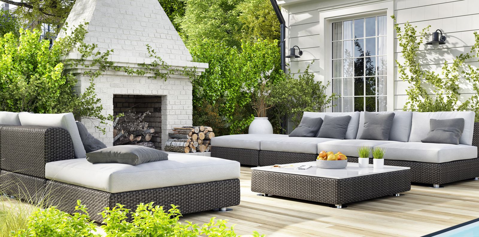 Outdoor floor model furniture arranged on a patio with seating and greenery at a showroom display