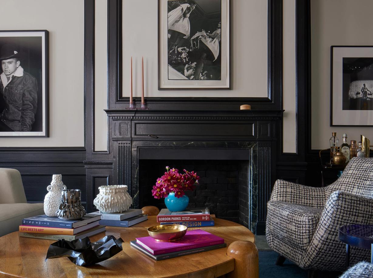 Moody living area with black fire place and wall paneling behind round wood coffee table