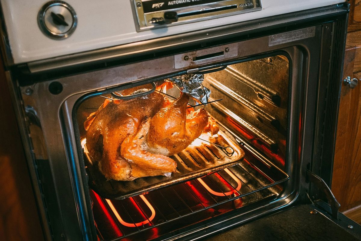 A foil-covered tray meal going into a hot oven to reheat