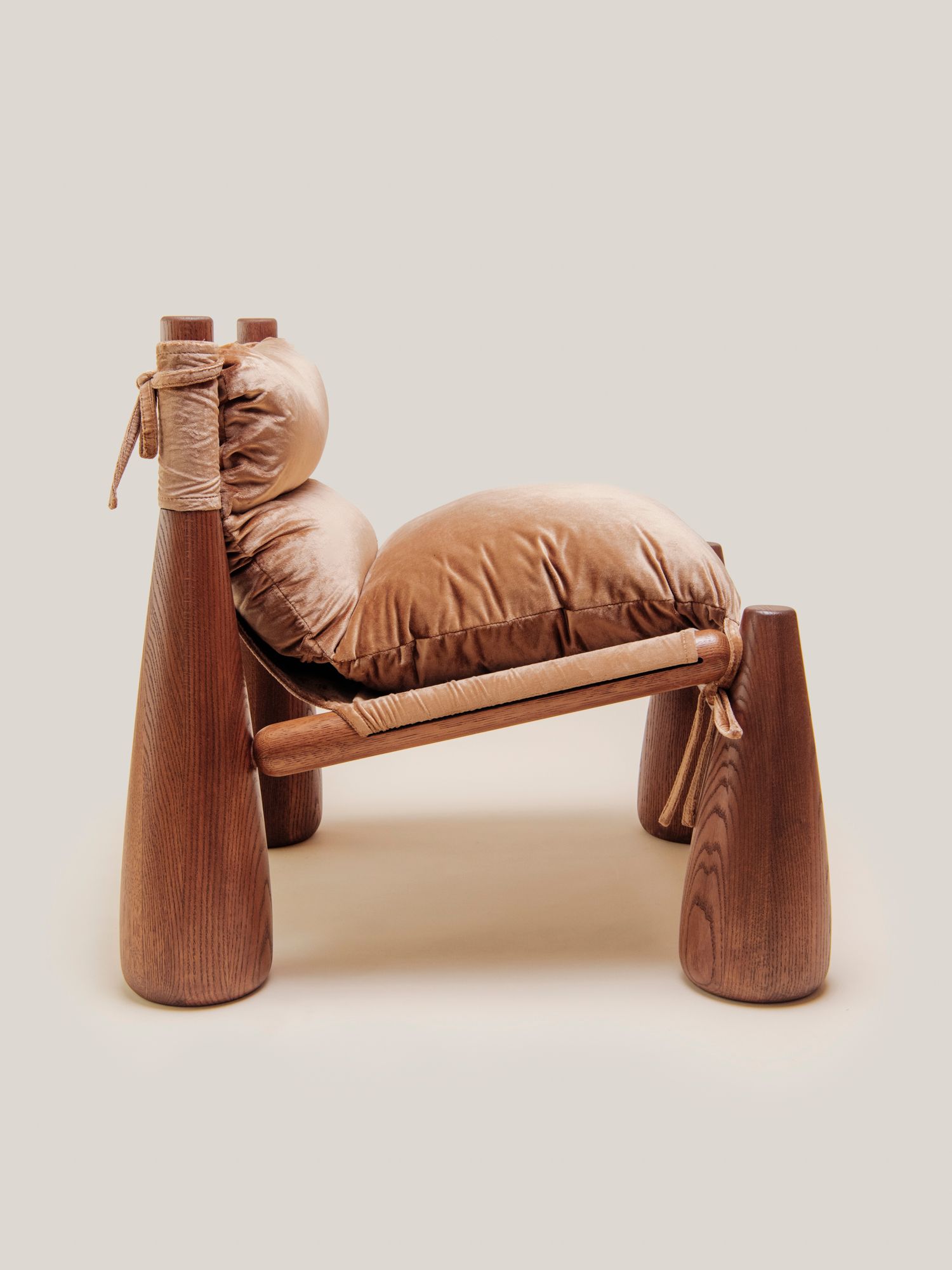A warm-toned lounge chair with rounded wooden legs and plush velvet CUSHIONS side view