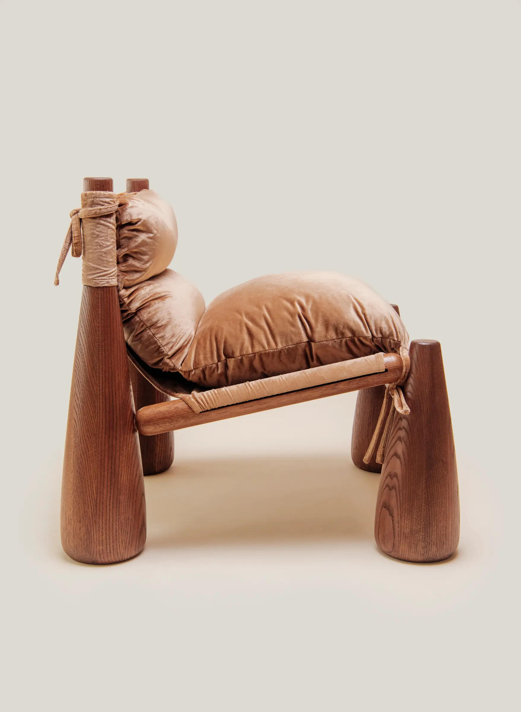 A warm-toned lounge chair with rounded wooden legs and plush velvet CUSHIONS side view