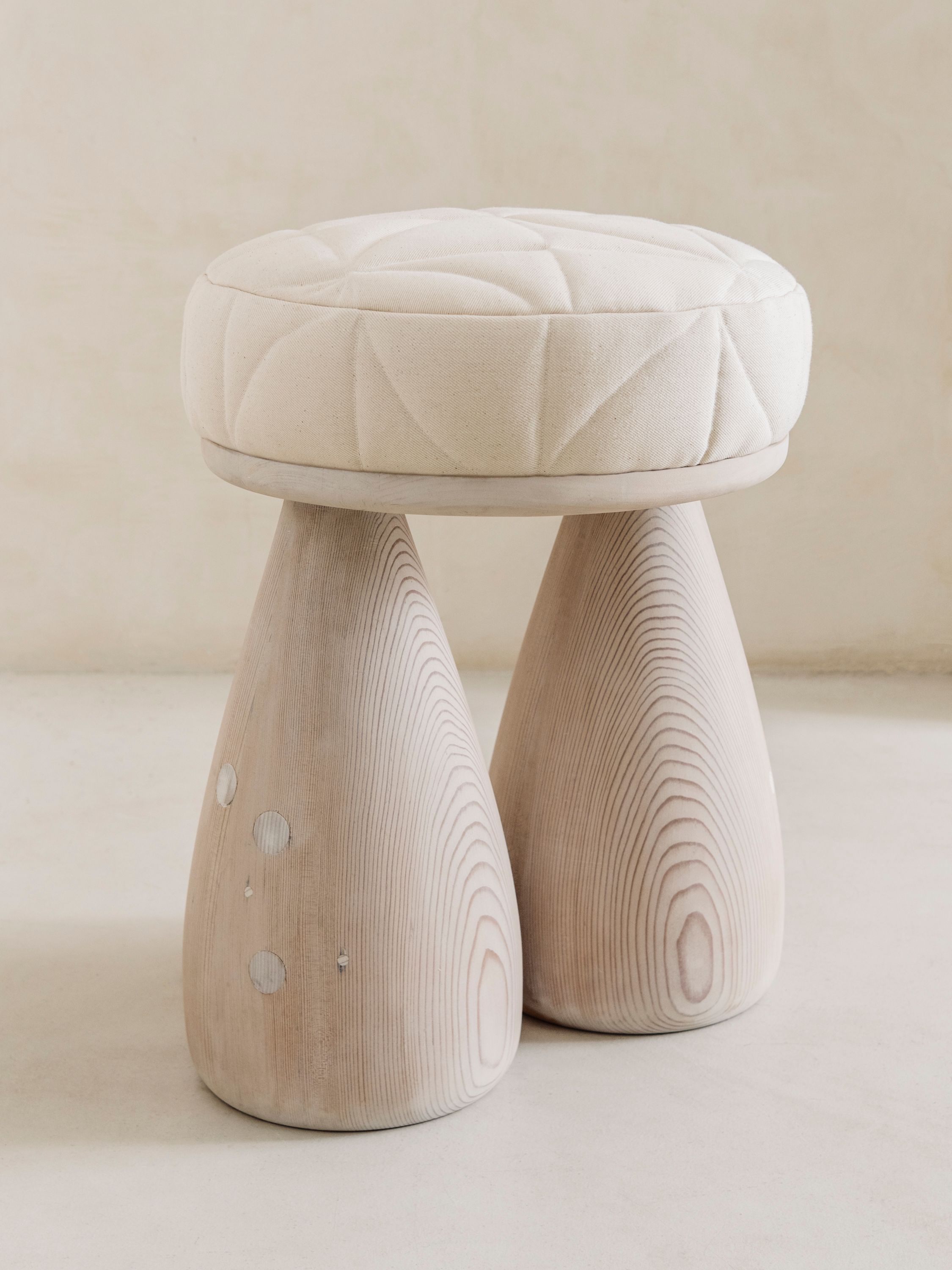 A plush stool with a cool toned finish, two legs in the shape of bell bottom jeans. 