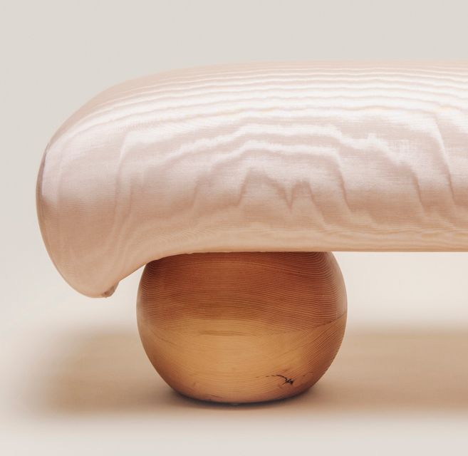 end view of bench with pink fabric and wood sphere legs