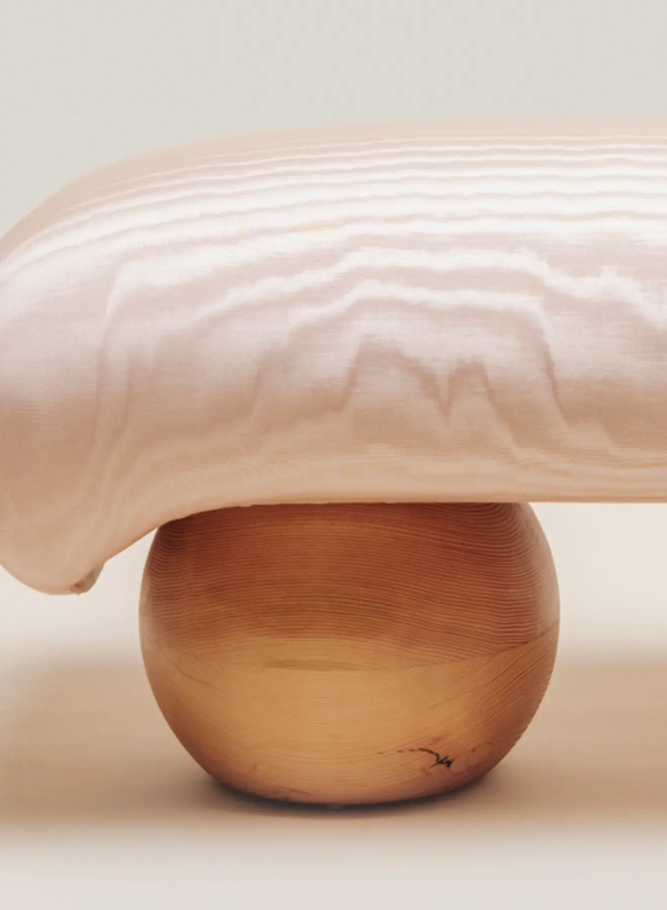 end view of bench with pink fabric and wood sphere legs