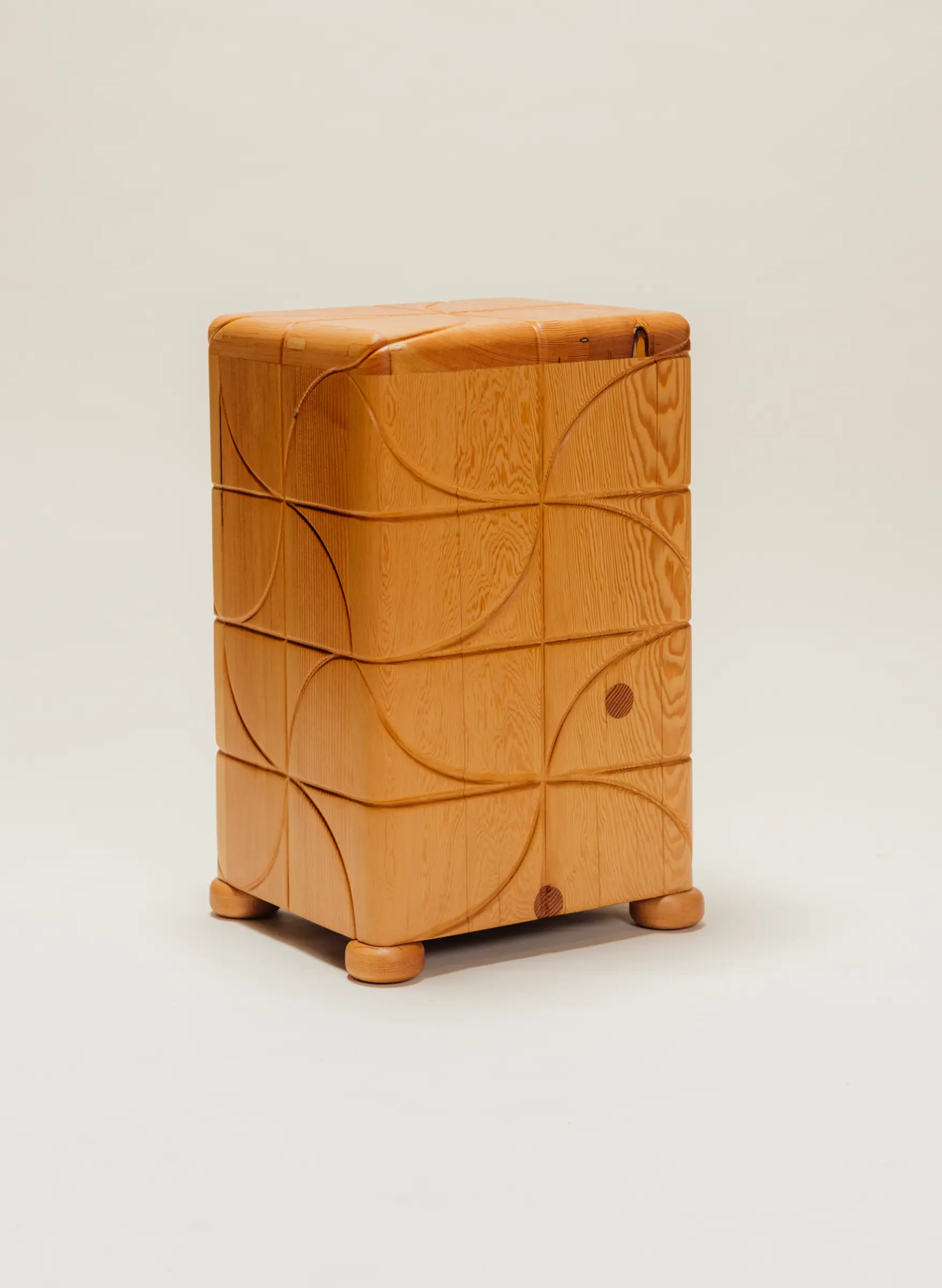 Wooden side table with a polished finish and carved pinwheel-inspired geometric patterns on all sides, standing on short rounded feet against a neutral background.