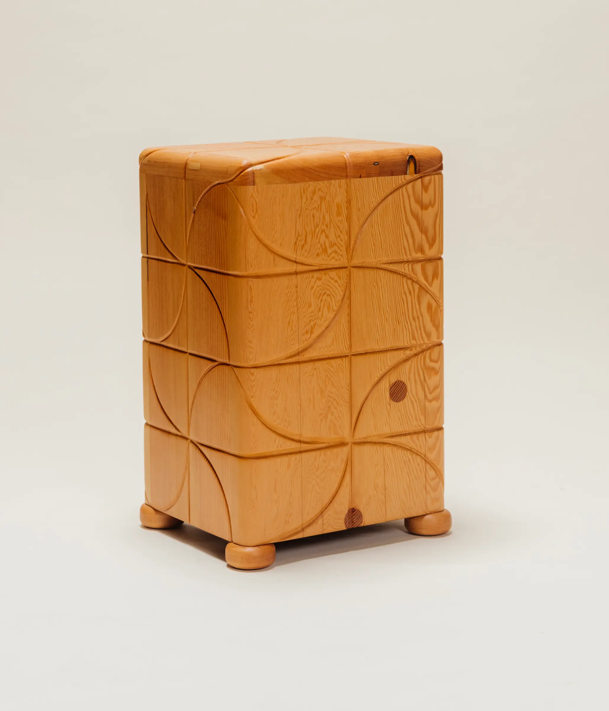 Wooden side table with a polished finish and carved pinwheel-inspired geometric patterns on all sides, standing on short rounded feet against a neutral background.
