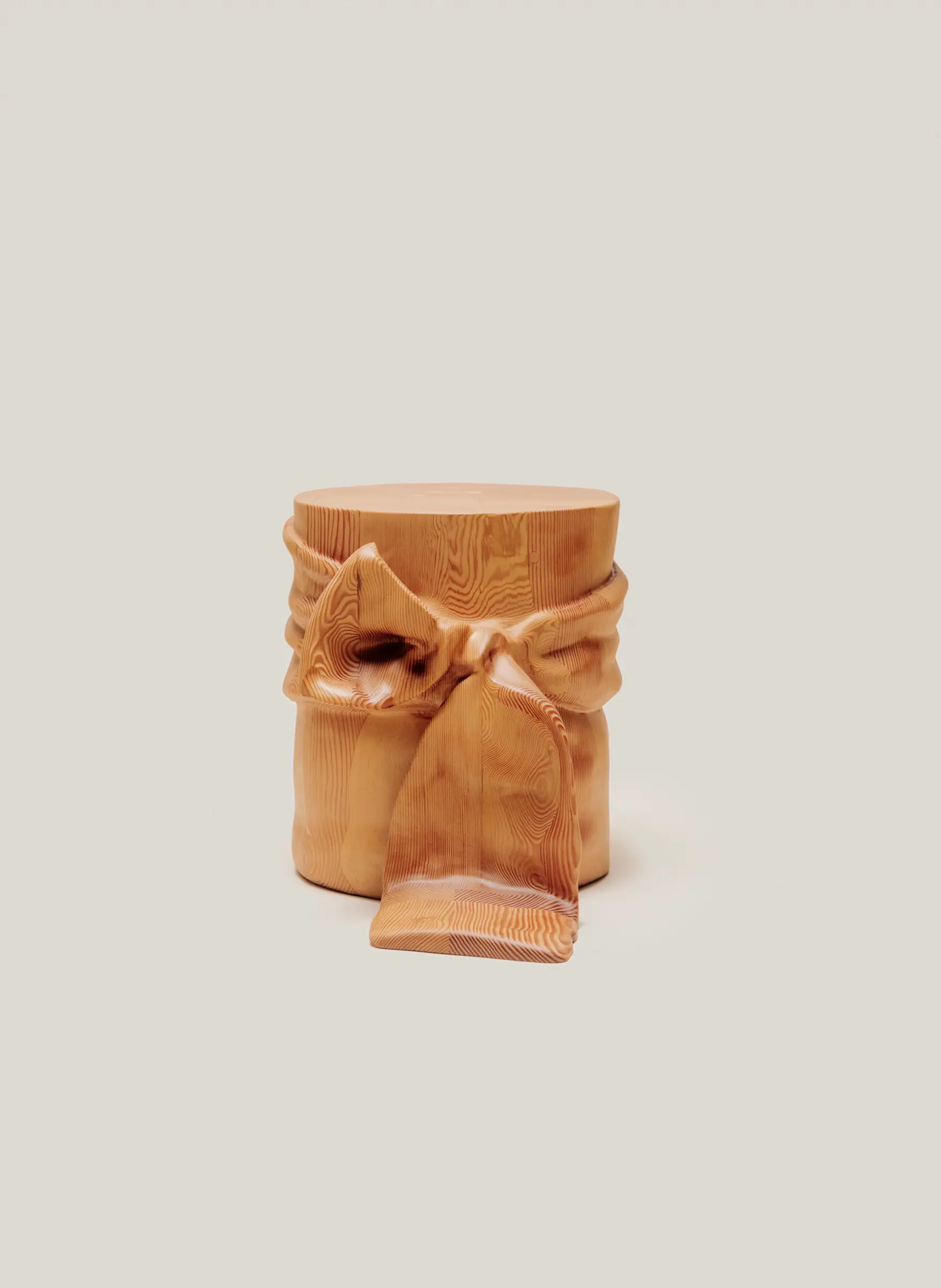 Wooden side table designed to resemble fabric tied into a ribbon bow, blending sculptural detail with functional form.
