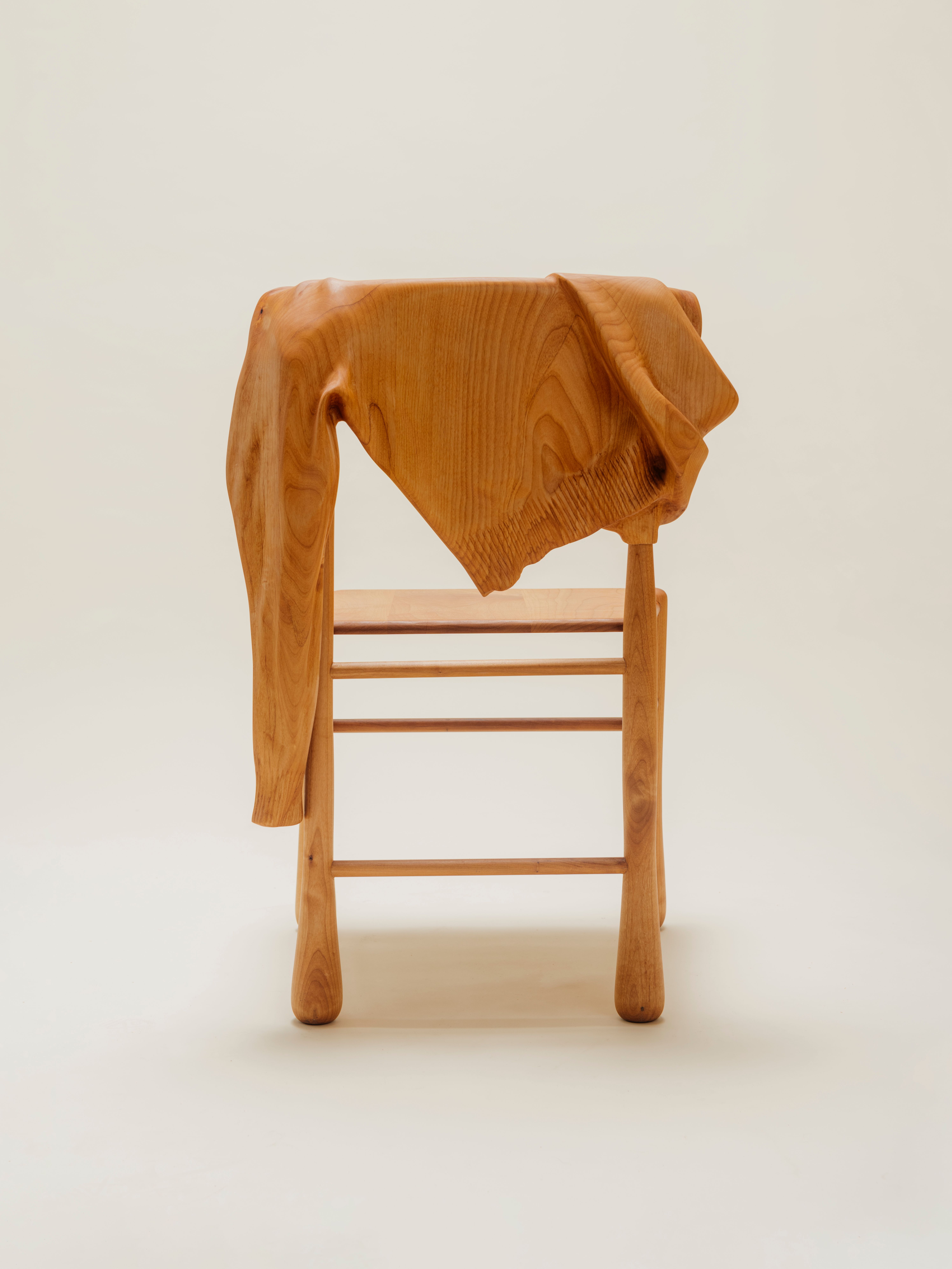 back of wooden chair with wood sweater hanging over it on a clean background.
