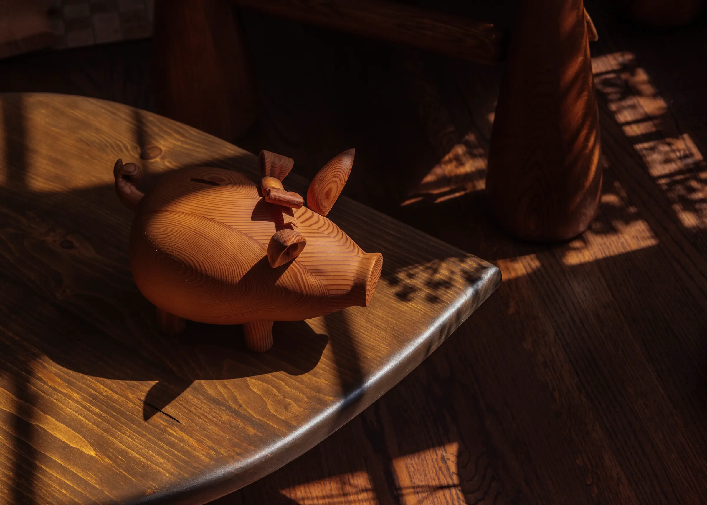 Wooden pig placed on a dark wooden table with shadows
