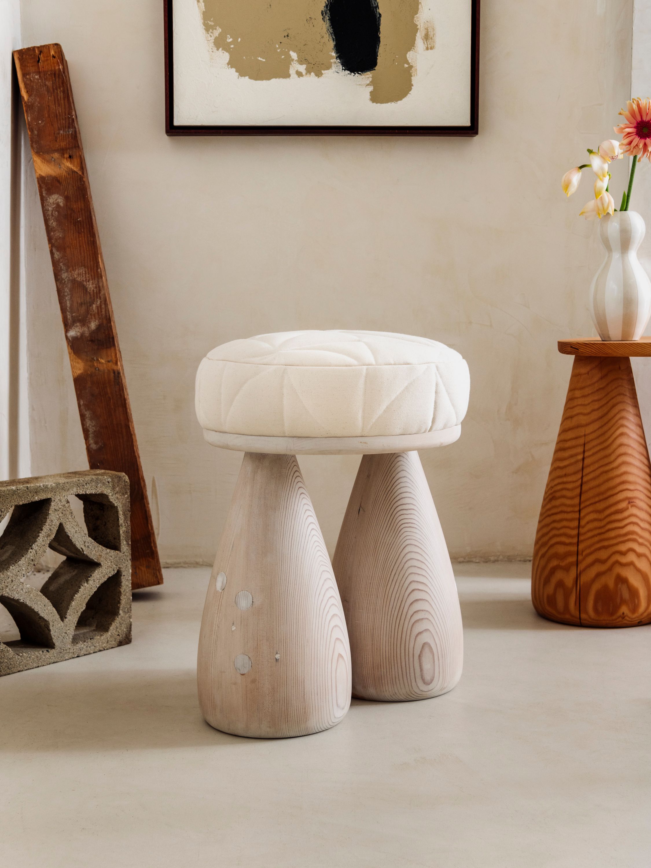 A plush stool with a cool toned finish, two legs in the shape of bell bottom jeans. 