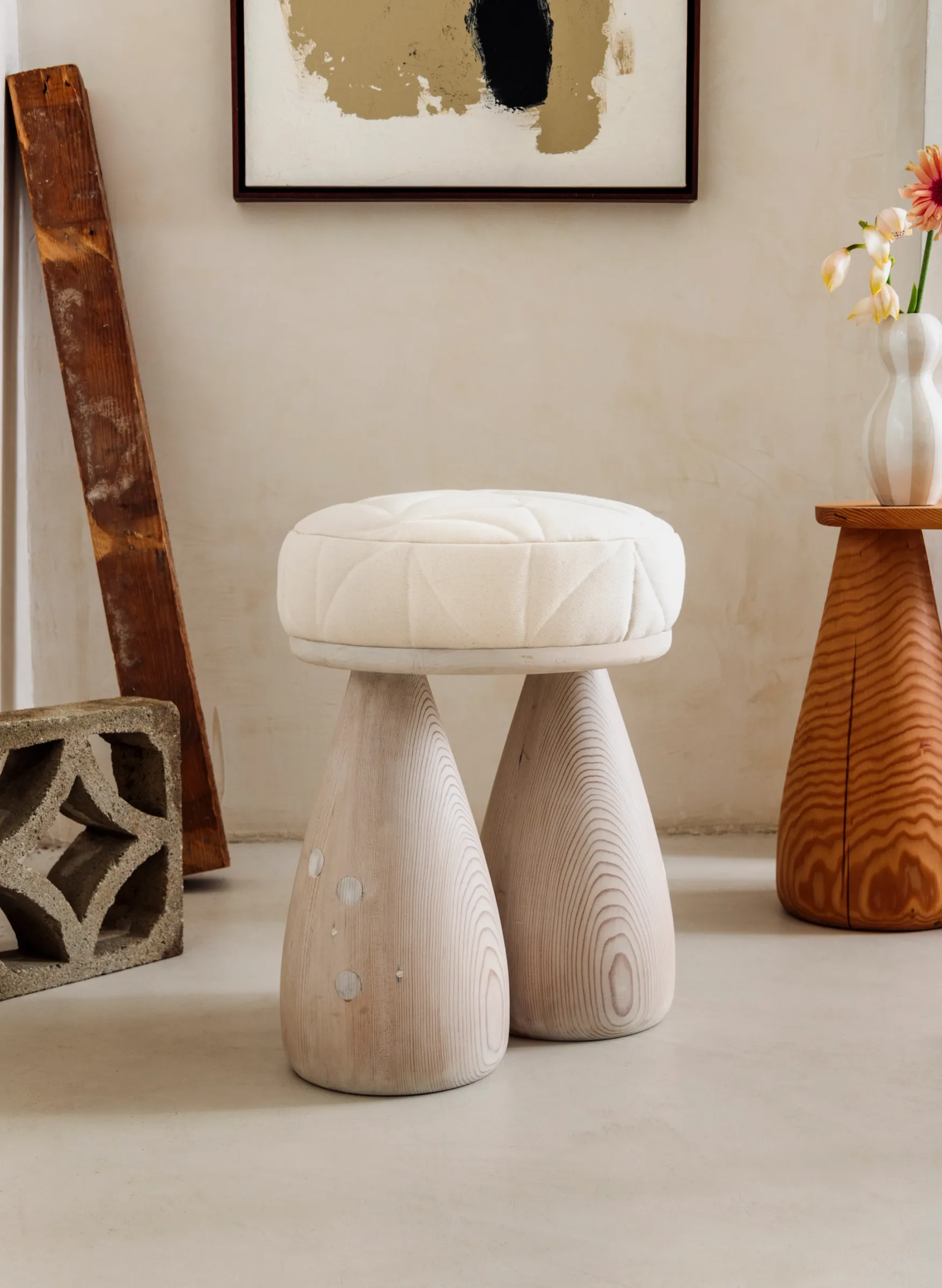 A plush stool with a cool toned finish, two legs in the shape of bell bottom jeans.