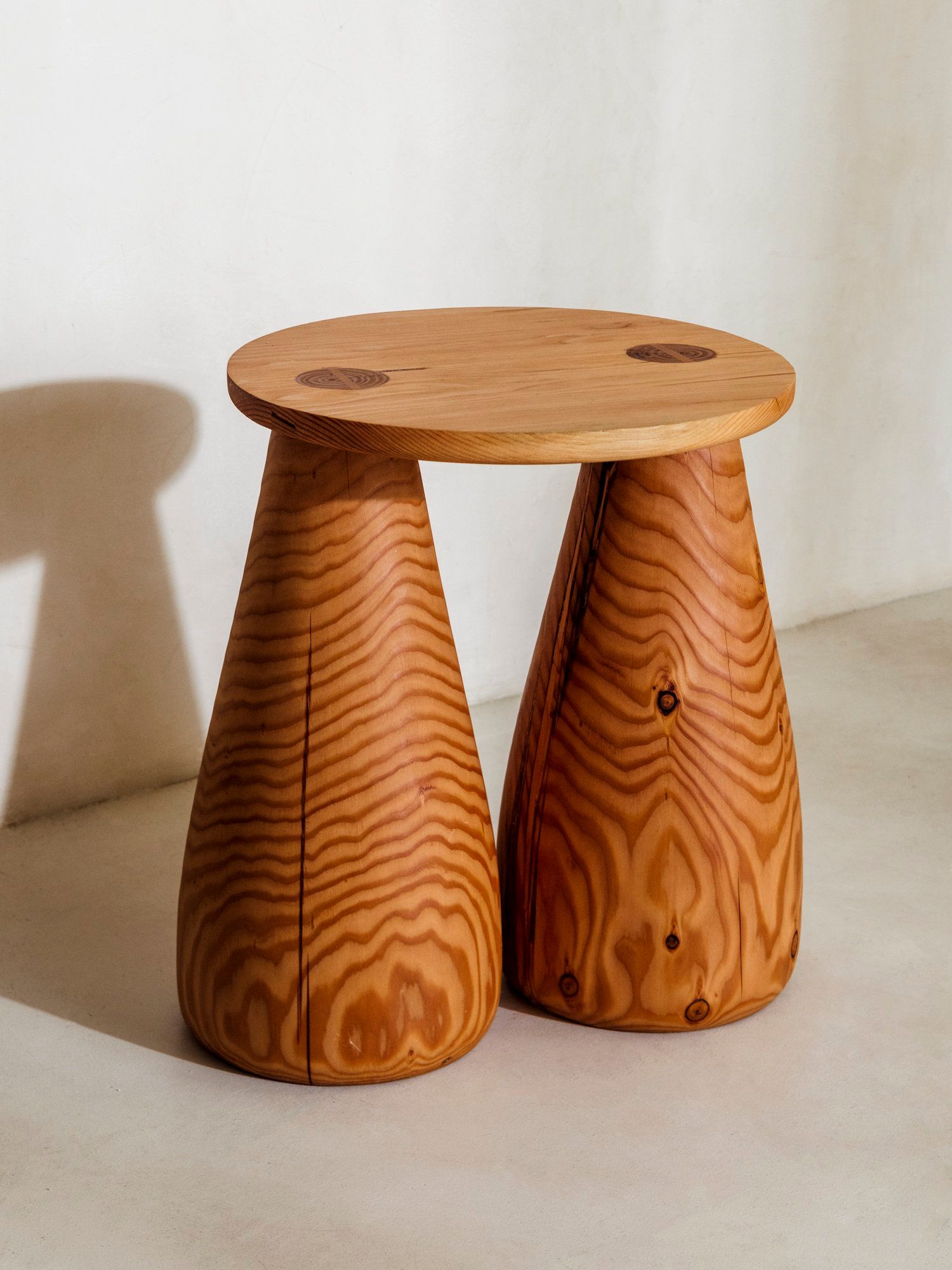 A wooden side table with sculpted legs and a round top.