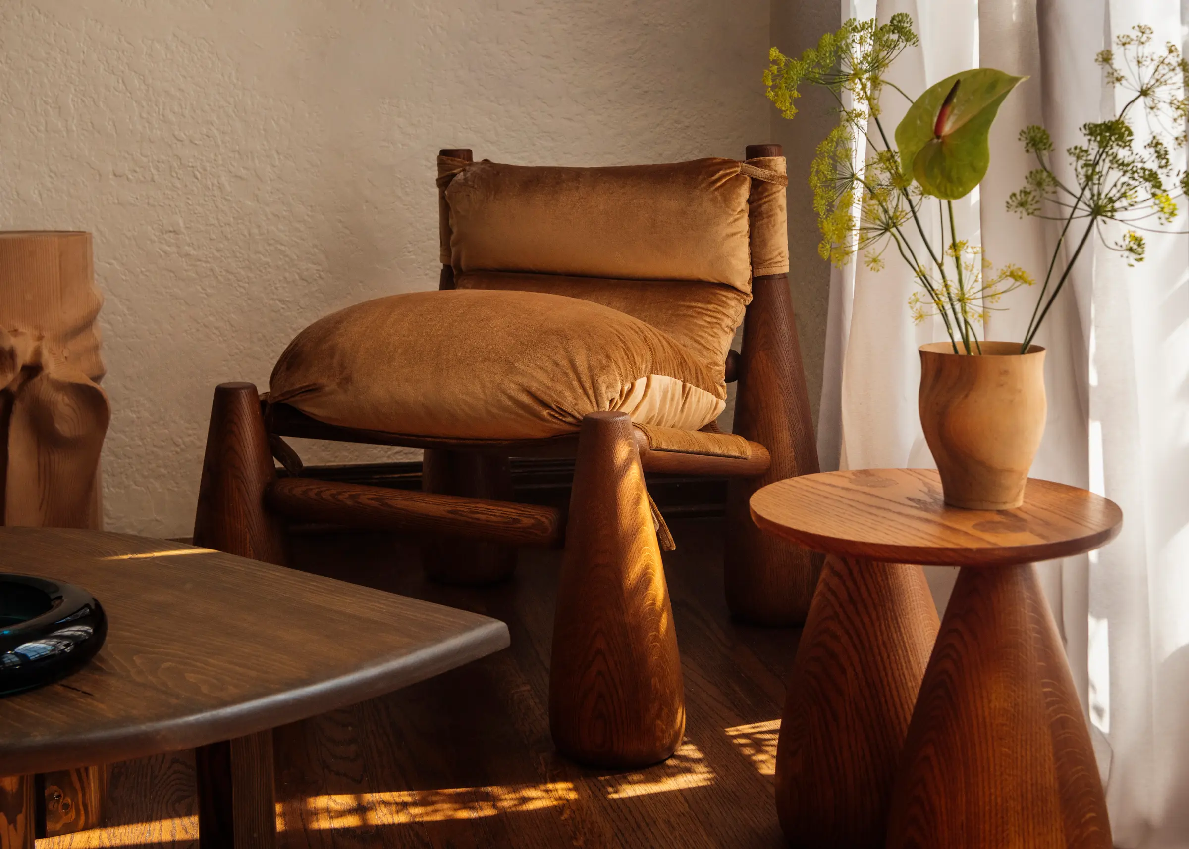 Bell chair with brown soft fabric placed next to a wooden table with a vase and plants
