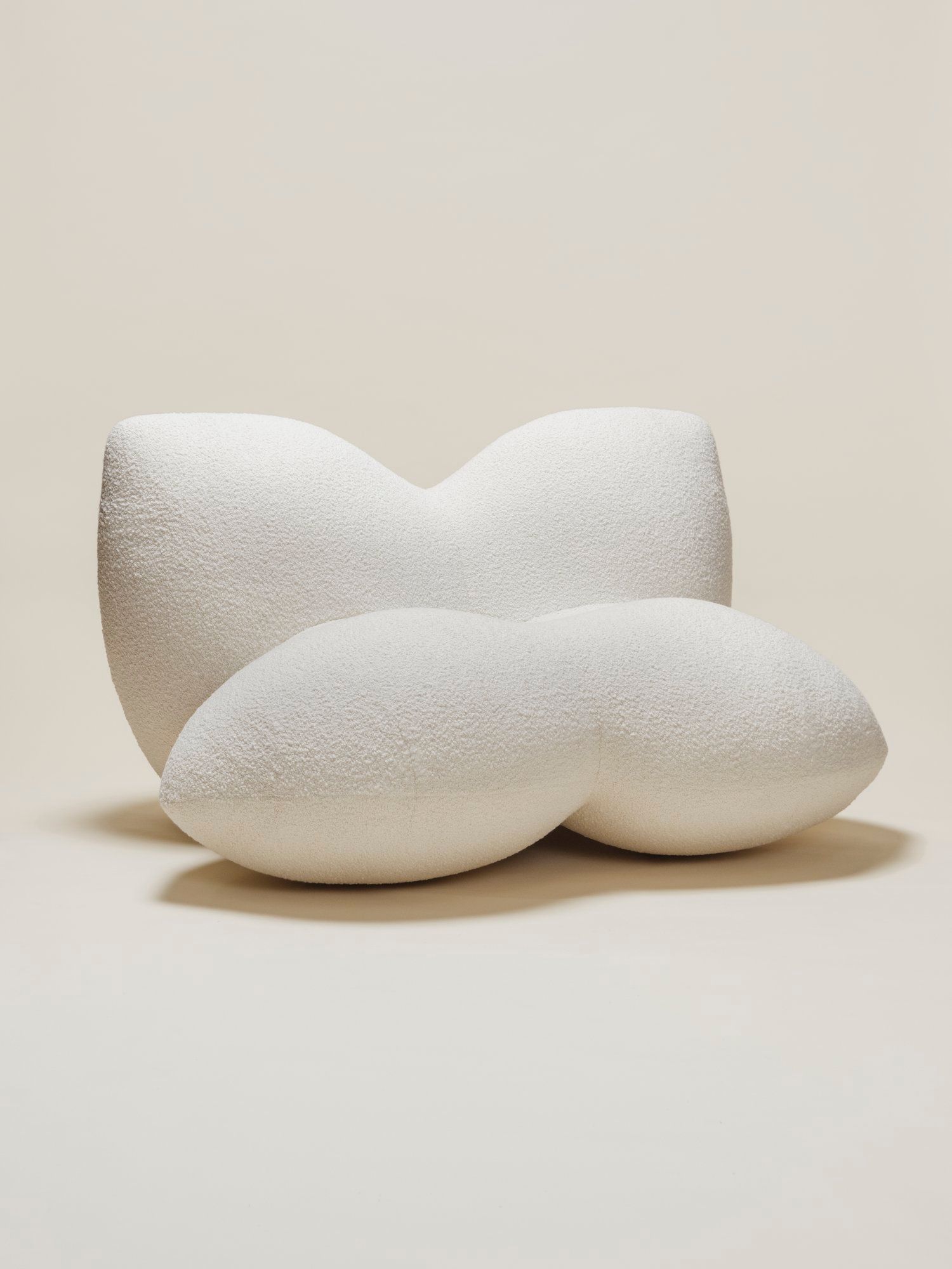 The Petal Chair by Studio Sam Klemick featuring soft, sculptural white upholstery with curved petal-like forms, blending comfort and organic design.