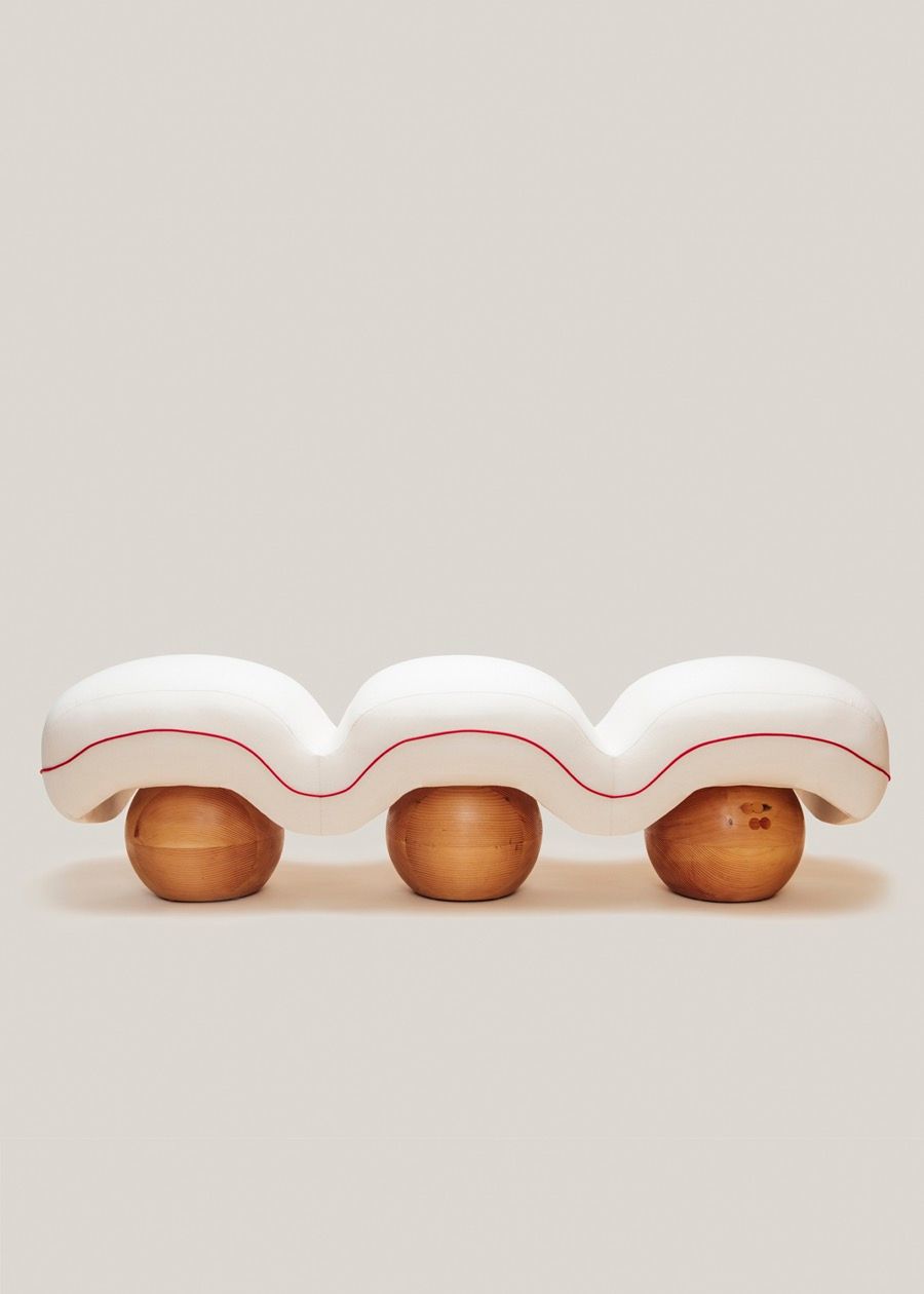 Sculptural upholstered bench with soft quilted curves and rounded wooden bases.