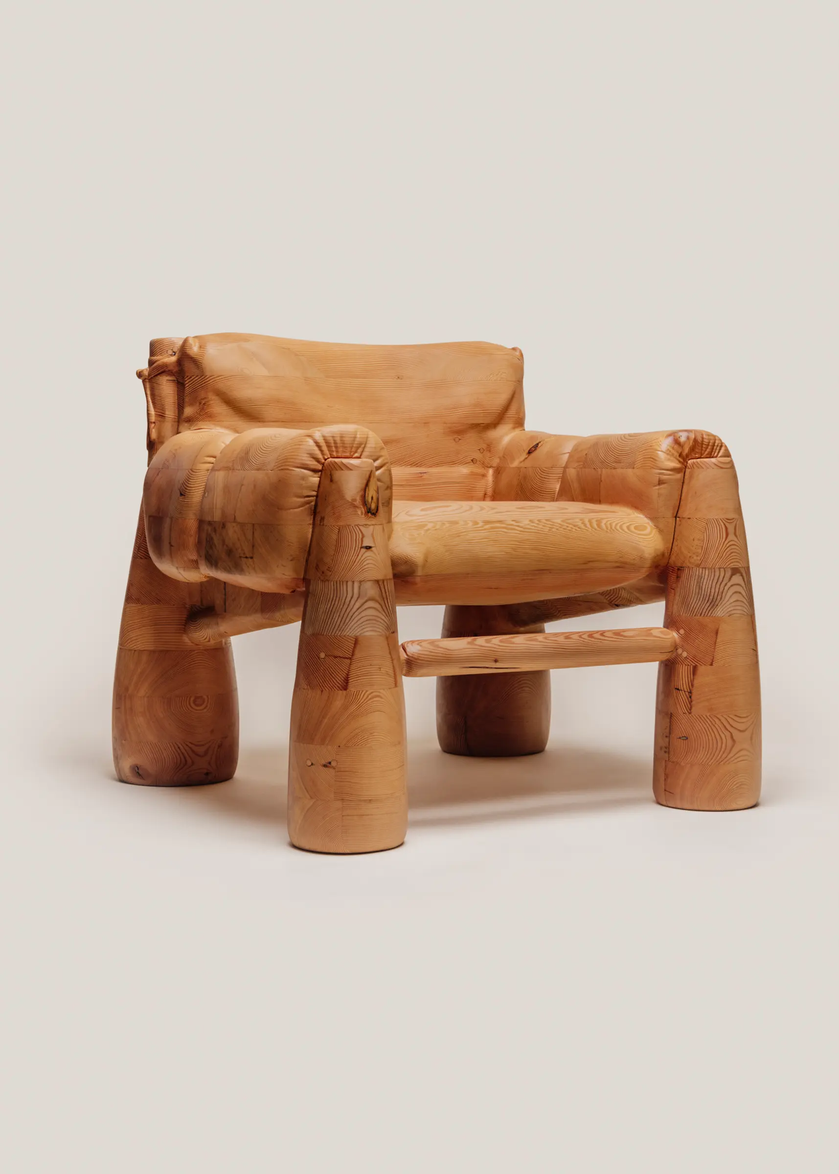 A large wooden armchair that is skillfully carved to look like a soft, overstuffed upholstered chair.