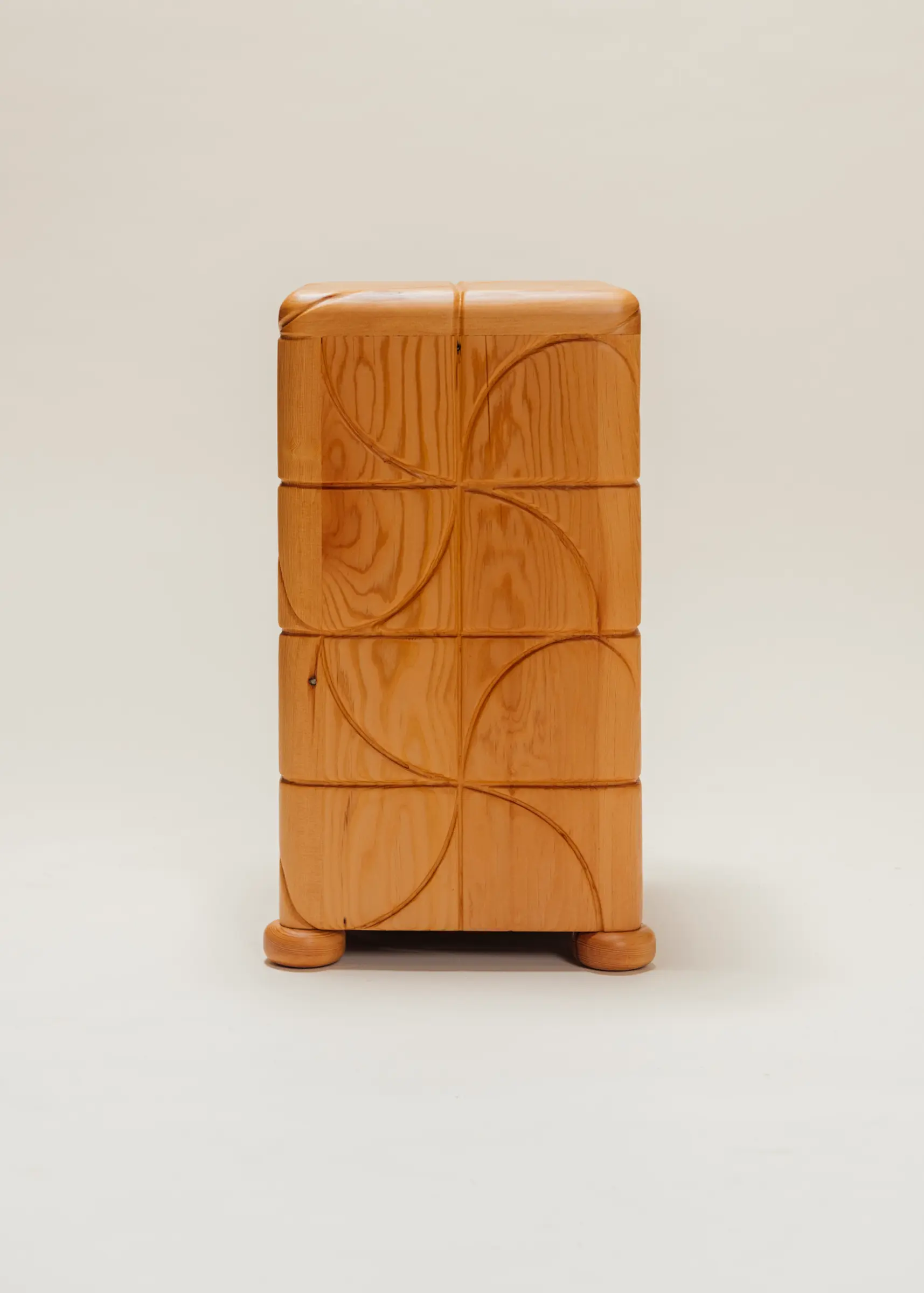 Wooden side table with a polished finish and carved pinwheel-inspired geometric patterns on all sides, standing on short rounded feet against a neutral background.