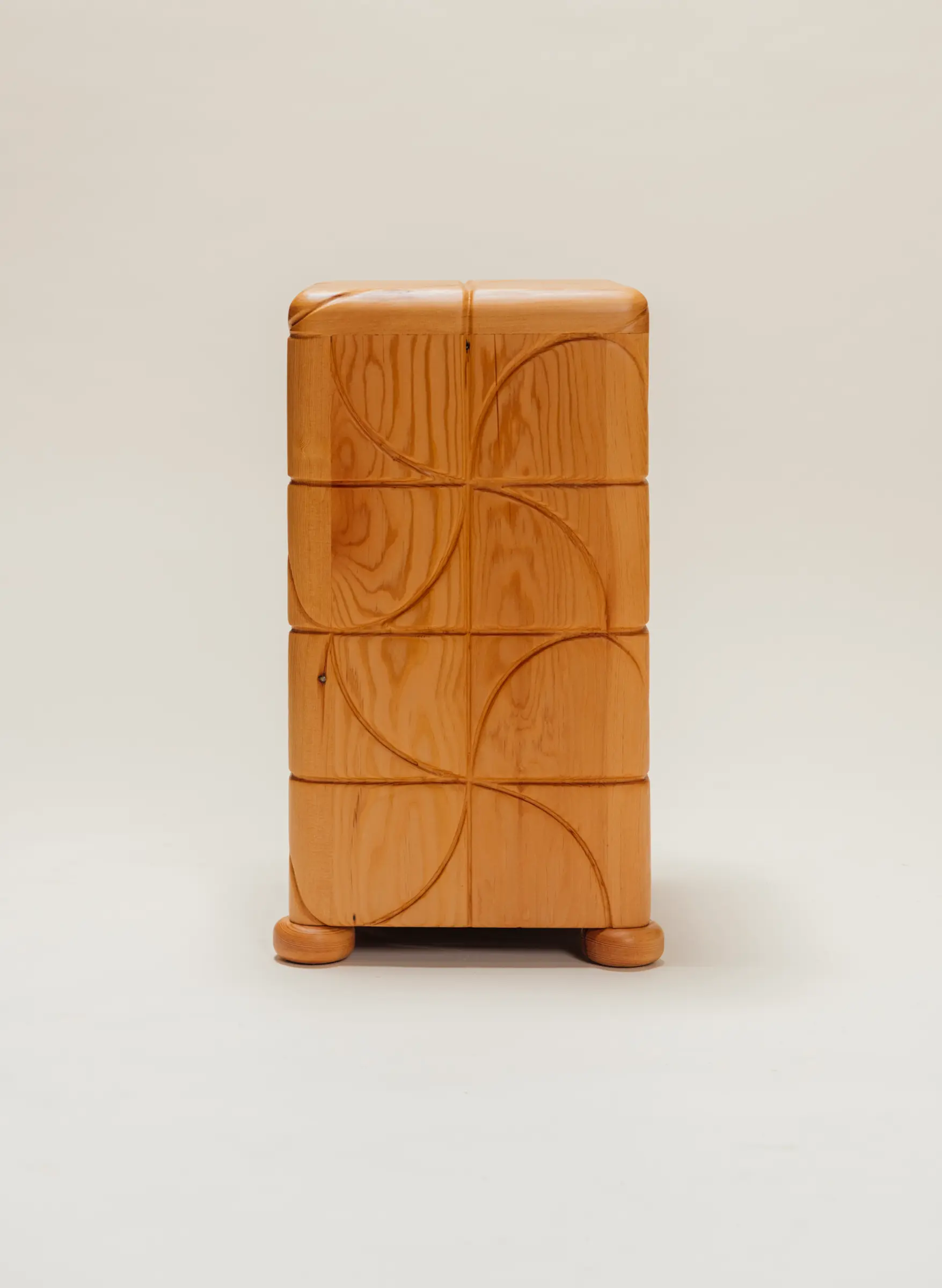 Wooden side table with a polished finish and carved pinwheel-inspired geometric patterns on all sides, standing on short rounded feet against a neutral background.
