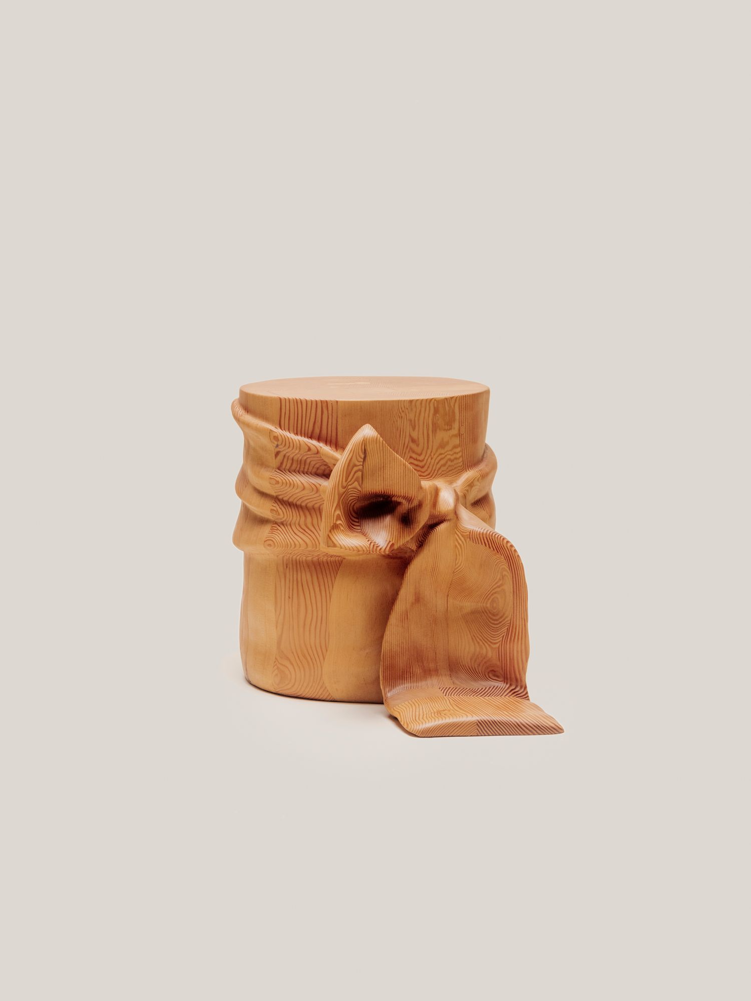 Wooden side table designed to resemble fabric tied into a ribbon bow, blending sculptural detail with functional form.