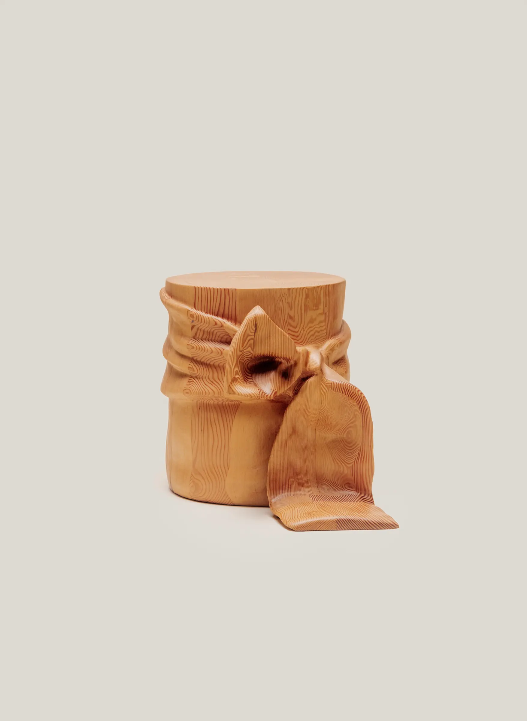 Wooden side table designed to resemble fabric tied into a ribbon bow, blending sculptural detail with functional form.