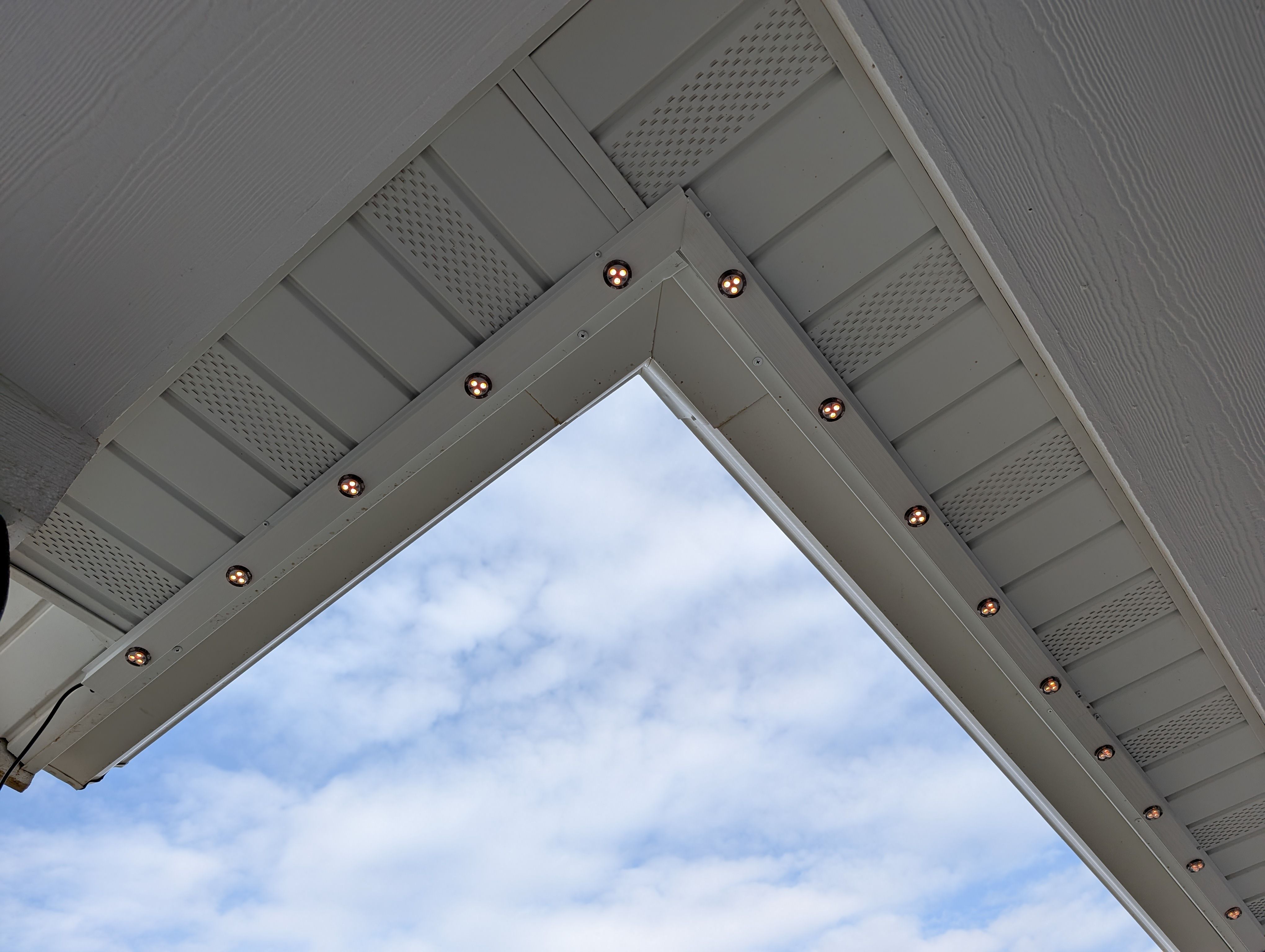 Professionally installed white track lighting with clean corners, no wires showing, and color matched to the house.