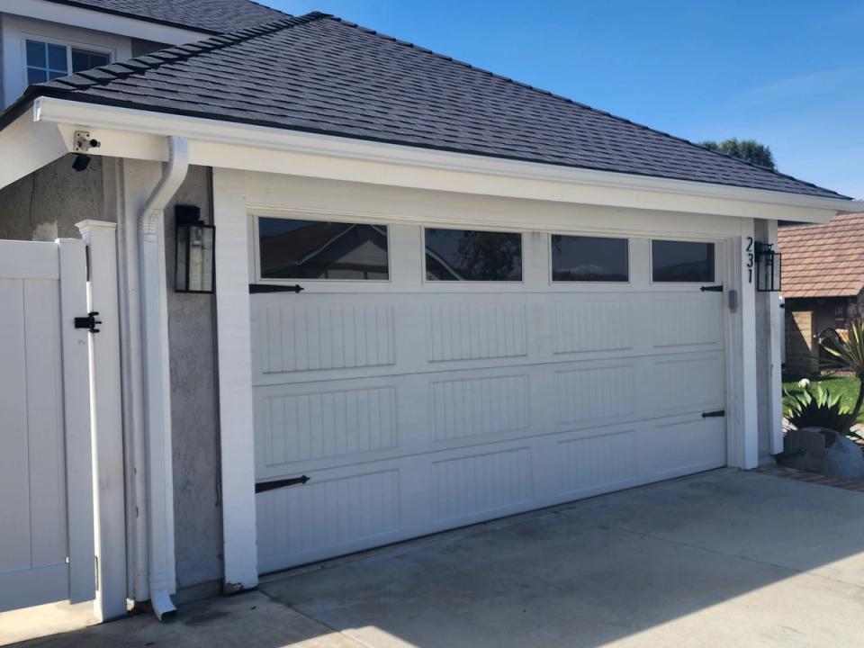 White seamless aluminum gutter and downspout along a garage