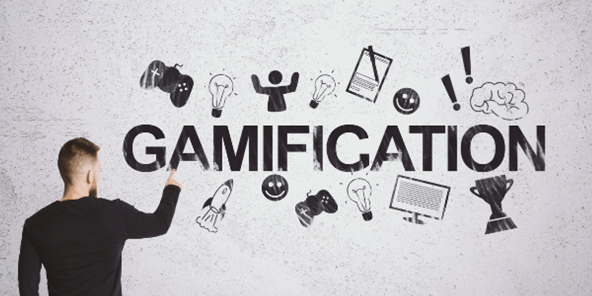 Man in black shirt writing gamification on whiteboard