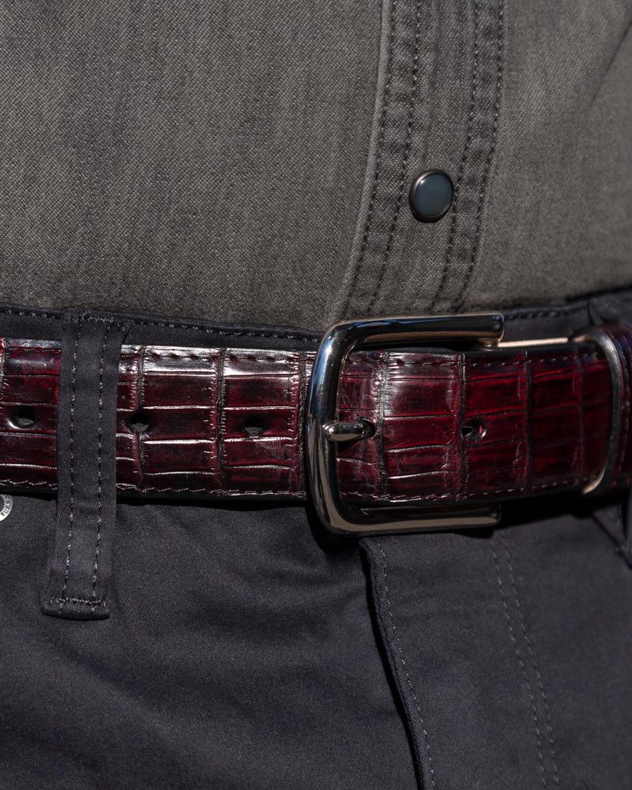 Black cherry crocodile belt close up on belt buckle around a man's waist