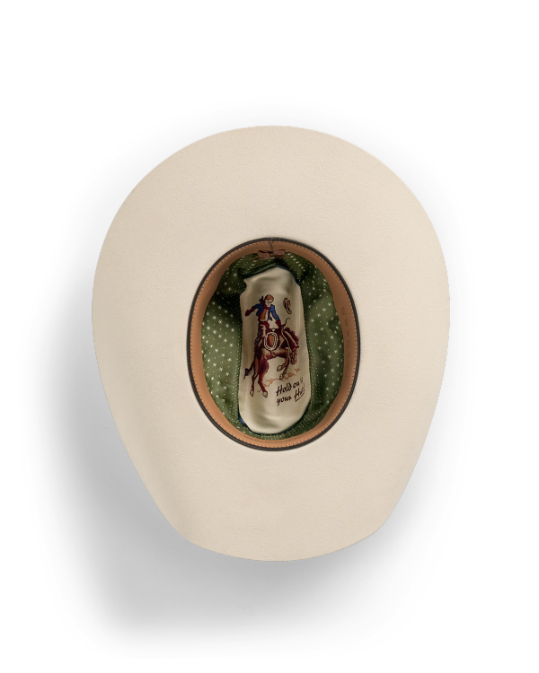 Top view of a beige cowboy hat with a green polka dot lining and an illustration of a cowboy riding a bucking horse on the inside crown.