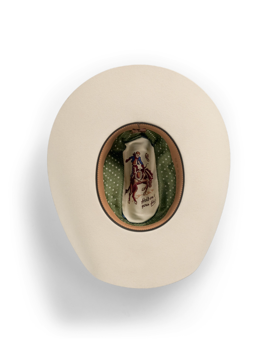 Top view of a beige cowboy hat with a green polka dot lining and an illustration of a cowboy riding a bucking horse on the inside crown.