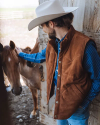 Man petting horse wearing suede jacket