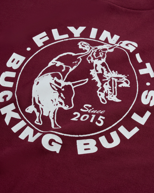 Maroon shirt with a white circular logo reading "Flying T's Bucking Bulls Since 2015," featuring a bull and a rodeo rider graphic.