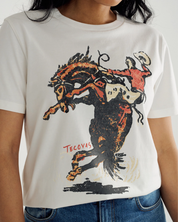 A person wearing a white t-shirt with a graphic of a bucking horse and rider, featuring the brand name "Tecovas" in red text.