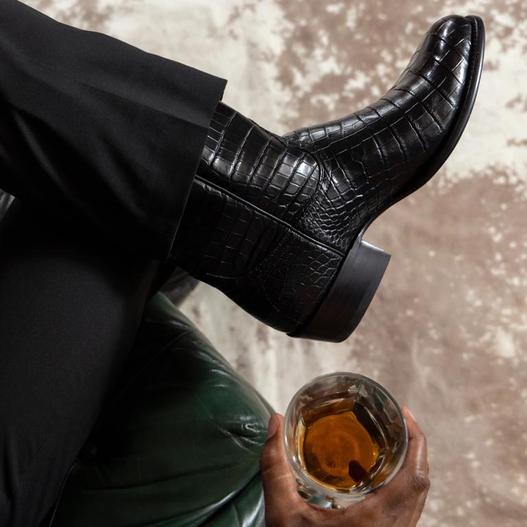 man drinking whiskey in fancy boots