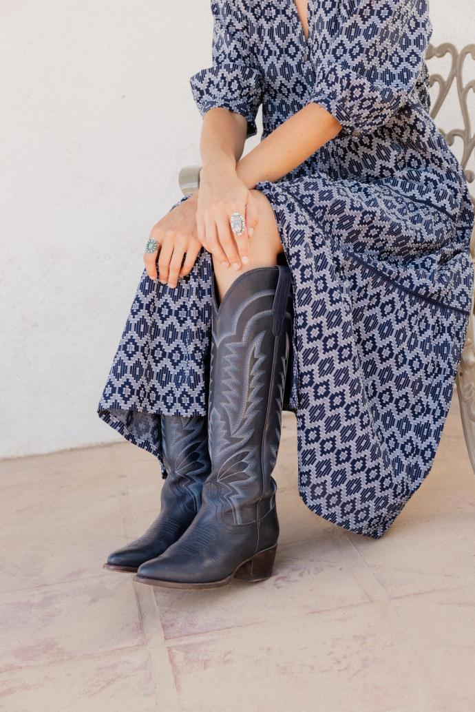 Closeup of woman sitting outside wearing a navy dress and navy boots