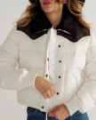 A woman wearing a white puffer jacket with a black collar is zipping up the front.
