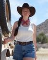 Woman on a ranch wearing a white tank top and jean shorts