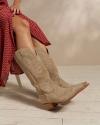 Closeup of woman putting on tan boots in a photo studio