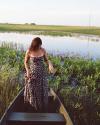 Woman wearing Kristopher Brock The Willow Dress standing in a canoe in a pond - Tecovas 